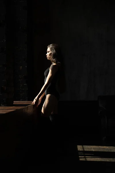Dziewczyna stoi w pobliżu okna w ciemnym pokoju — Zdjęcie stockowe