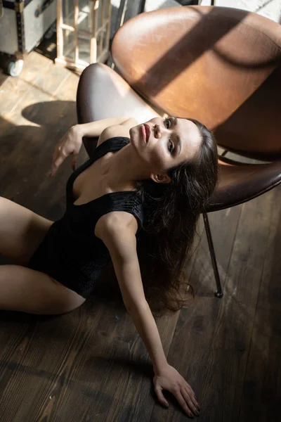 Flicka med mörkt hår på bakgrund av läder stol — Stockfoto