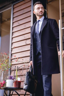 Nazik genç adam cam kapının yanında duruyor.