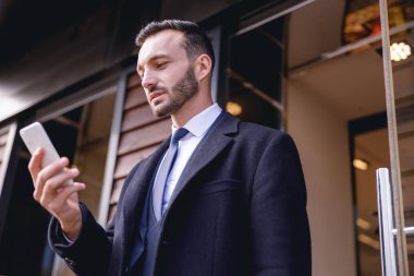 Akıllı telefonuna dikkat eden genç bir işadamı.