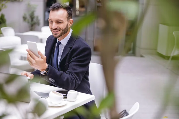 Vrolijke jonge kantoormedewerker brengt zijn vakantie door in café — Stockfoto