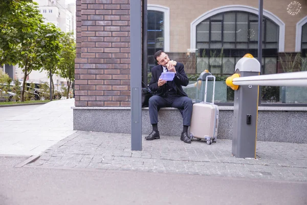Hladový brunetka muž sedí u jeho kufru — Stock fotografie