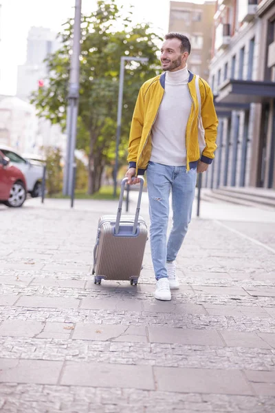 Knappe jonge man die met zijn koffer zwaait — Stockfoto