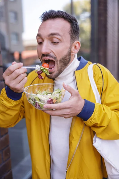 Hongerige man met baard die verse salade eet tijdens de wandeling — Stockfoto