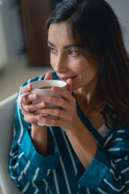 Gülümseyen bayan sabah kahvesinin tadını çıkarıyor.