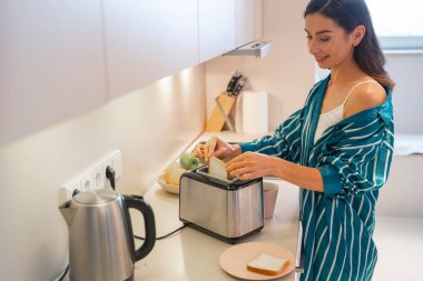 Mutfak fotoğrafında gülümseyen kadın kahvaltı hazırlıyor.