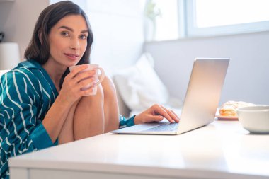 Hafta sonu ev yapımı fotoğraf çekiminde sıcak çay ve dizüstü bilgisayar.