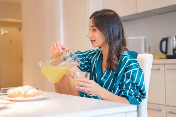 Mulher calma derramando suco na cozinha foto stock — Fotografia de Stock