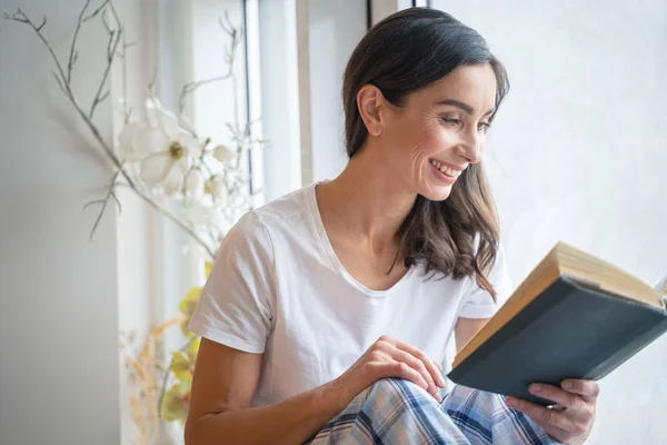 Glimlachende vrouw leest een grappig verhaal stockfoto — Stockfoto