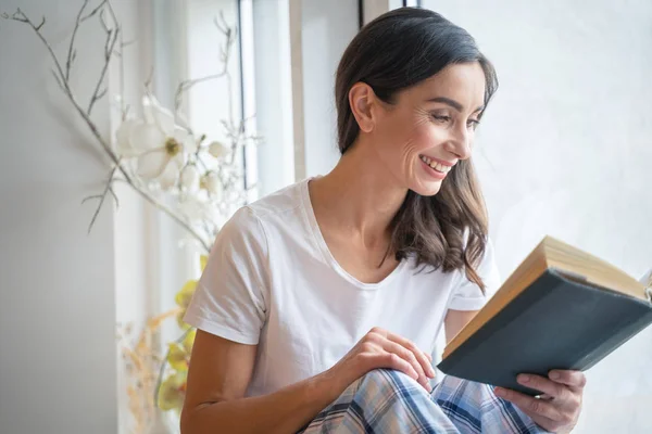 Mujer sonriente leyendo una historia divertida stock foto — Foto de Stock