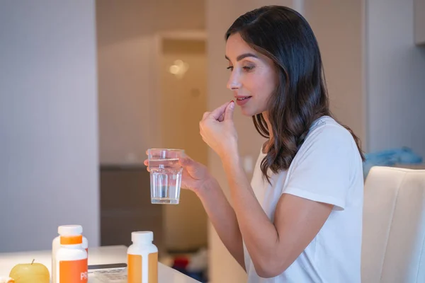 Mujer tranquila con pastillas y vaso de agua —  Fotos de Stock