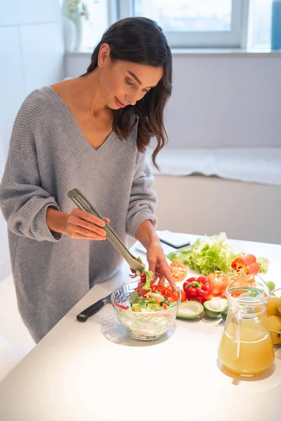Sorrindo senhora cuidadosamente misturando salada fresca foto stock — Fotografia de Stock