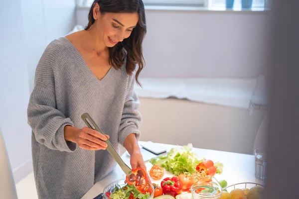 Senhora sorridente na cozinha com pinças de salada foto stock — Fotografia de Stock
