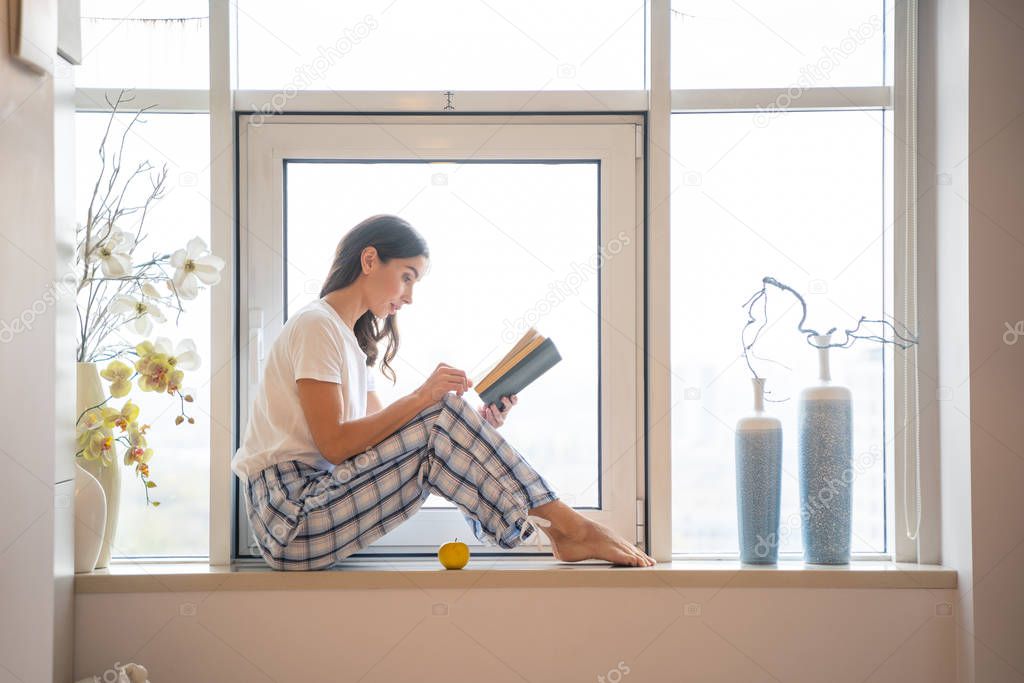 Calm woman on the windowsill with book stock photo