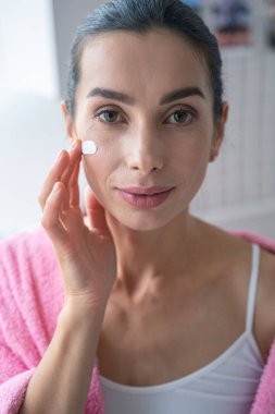 Güzel yüz kremi kullanan gülümseyen bayan.