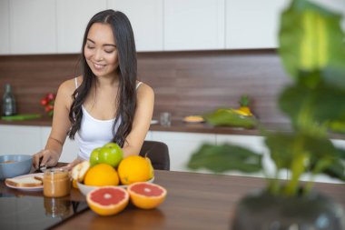 Gülümseyen güzel Asyalı kadın kahvaltısını hazırlıyor.
