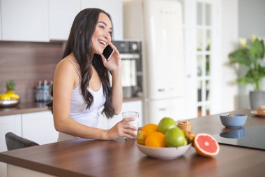 Güzel bir kadın mutfak masasında oturuyor.