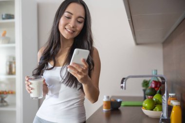 Mutlu kadın cep telefonuna bakıyor.