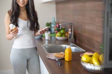 Kadın vitamin şişesinde etiketi okuyor.