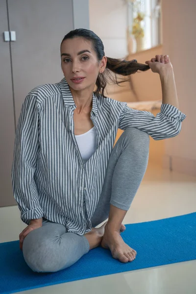 Yoga minderindeki kadın saç tokası fotoğrafına dokunuyor. — Stok fotoğraf