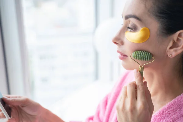 Femeie cu patch-uri de ochi folosind masaj de jad fotografie stoc — Fotografie, imagine de stoc