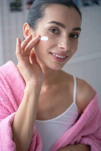 Sentirse feliz mientras se utiliza la crema facial foto de stock — Foto de Stock