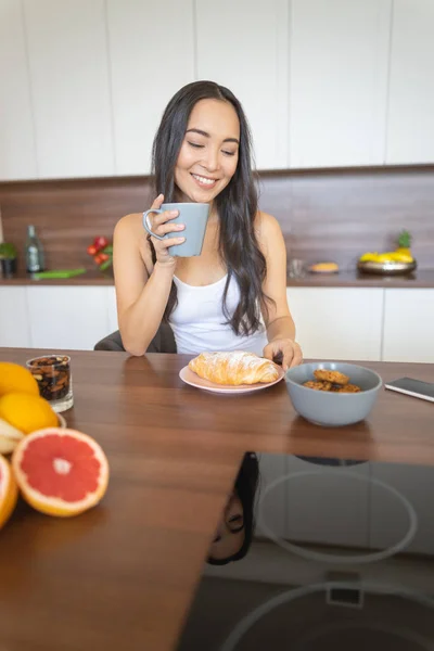 Молодая женщина ест одна на кухне — стоковое фото