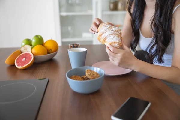 Kvinna som tar ett mellanmål med en croissant — Stockfoto