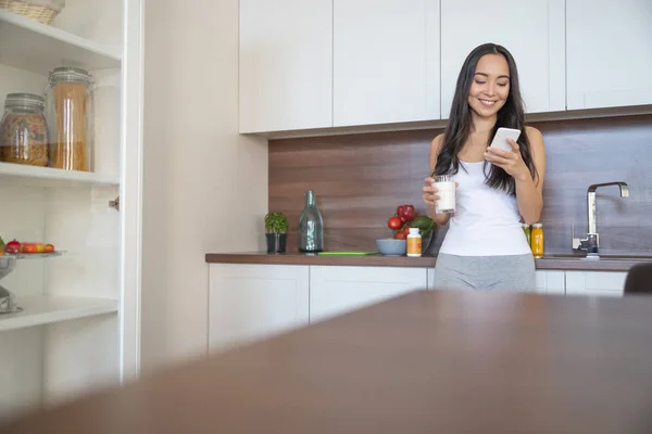 台所できれいな女性の飲料牛乳 — ストック写真