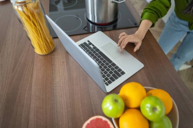 Genç Asyalı kadın aşçı dizüstü bilgisayara dokunuyor.
