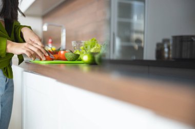 Kadın bıçakla domates kesiyor.