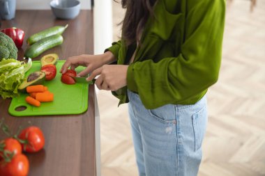 Genç ev hanımı tahtada domates doğruyor.