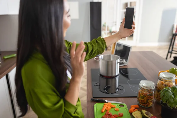 Домохозяйка со смартфоном на кухне — стоковое фото