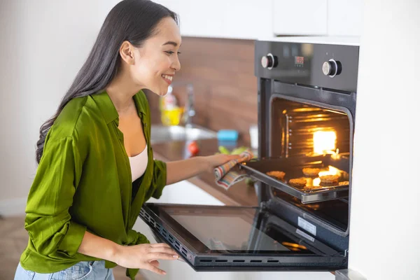 Sorrindo jovem dona de casa assar na cozinha — Fotografia de Stock