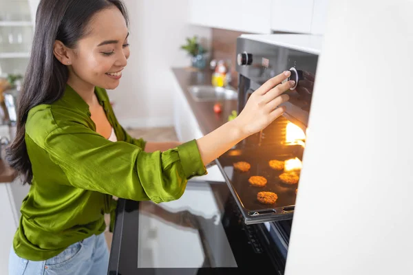 Mulher bonita abrindo o forno em casa — Fotografia de Stock