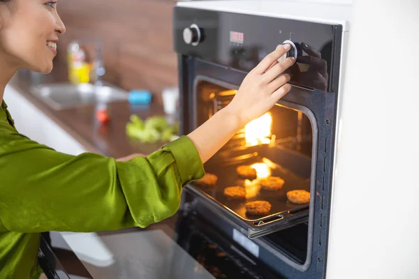 Smiling young woman setting the oven timer — Stockfoto