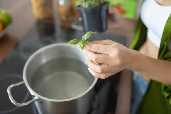 Woman leaning over the pot with water — Stock Photo, Image