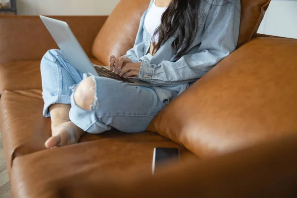 Девушка со скрещенными ногами сидит на диване — стоковое фото