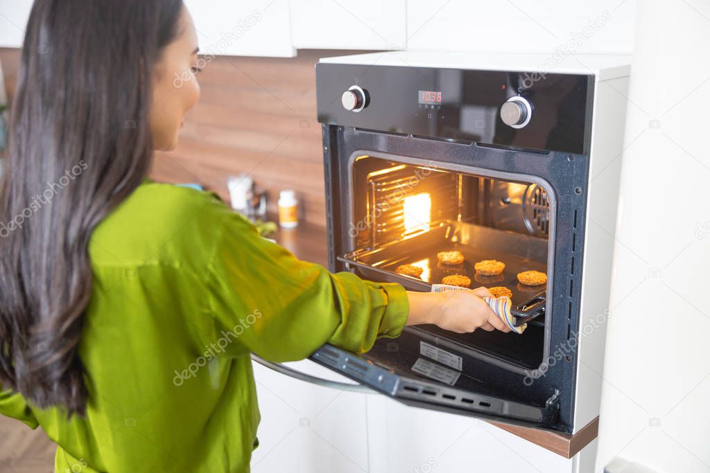 Woman taking the biscuits out of the oven