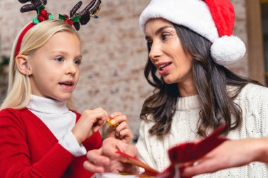 Noel Baba şapkalı anne kızına bakıyor.