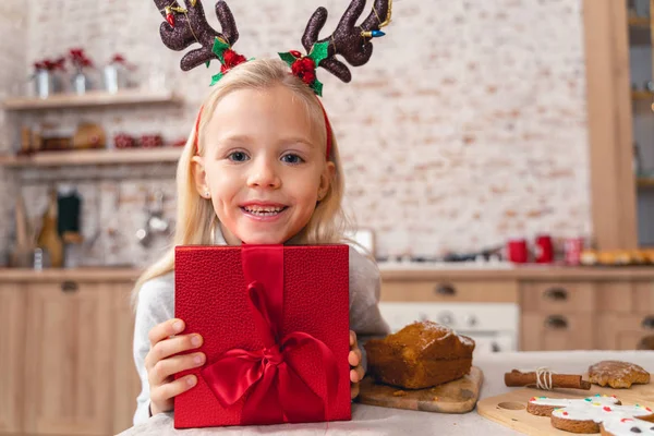Liebliches Kind mit einem Geschenk, das in die Kamera lächelt — Stockfoto