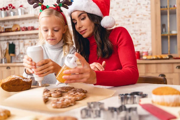 Fokuserat barn och hennes mamma dekorera kex — Stockfoto
