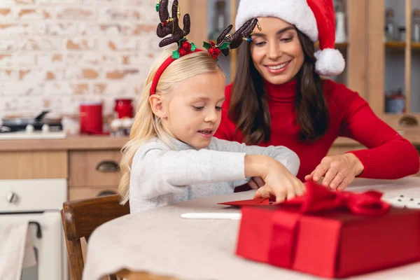 Vrolijke huisvrouw zitten met haar schattige dochter — Stockfoto