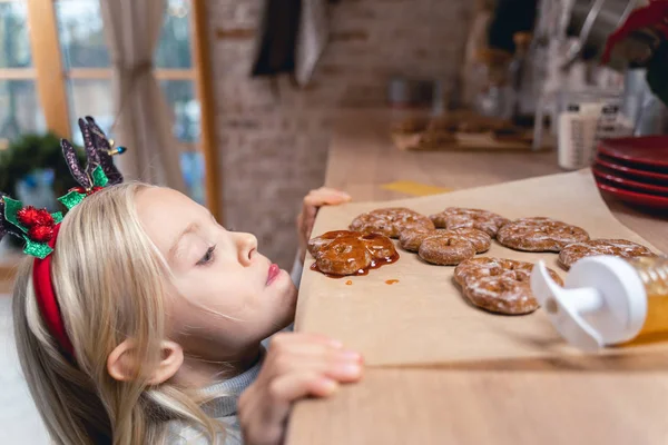 Niña hambrienta mirando galletas de jengibre — Foto de Stock