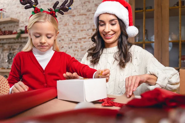 Fille et un parent enveloppant un cadeau — Photo