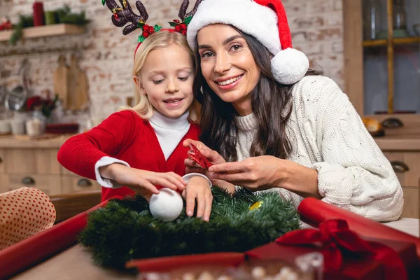 Madre sorridente che tiene un fiocco di ghirlanda di Natale — Foto Stock