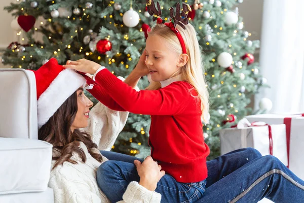 Chica jugando con su madre cerca del árbol de Navidad —  Fotos de Stock