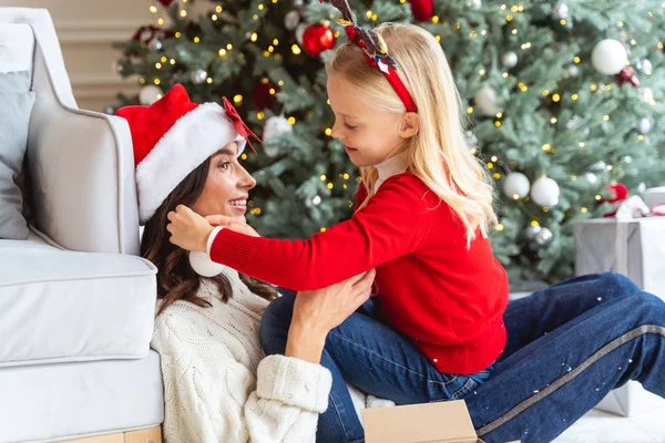 Ragazza con una palla di Natale seduta su uno stomaco delle donne — Foto Stock