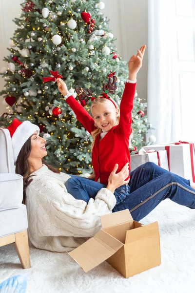 Weibliches Kind sitzt mit ihrer fröhlichen Mutter — Stockfoto