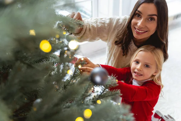 Heureuse femme au foyer et son enfant accrochant les ornements — Photo